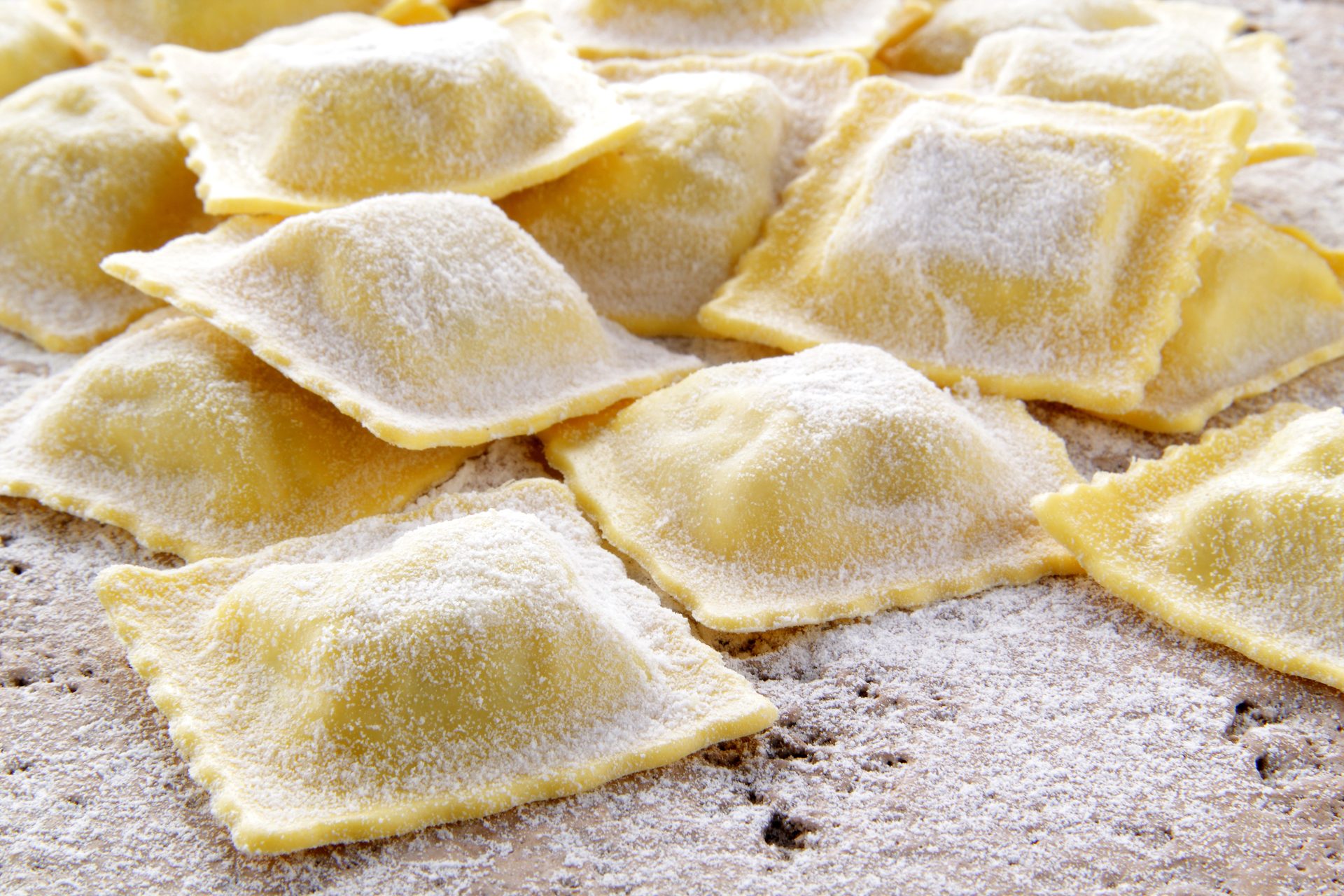 Ravioli quadrati di pasta fresca appena chiusi a mano e spolverati di farina sul piano di lavoro